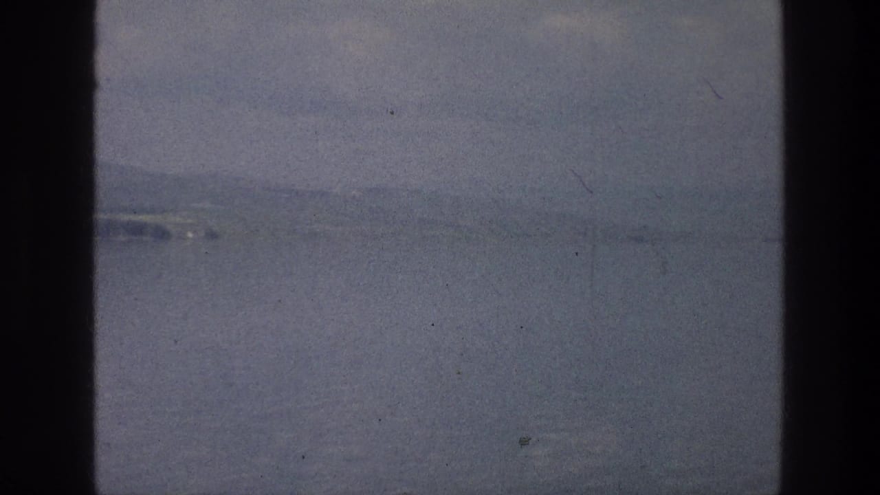 Sea of Galilee landscape in soft 8mm color, showing still water, haze, distant shore, and muted blue-gray tones.