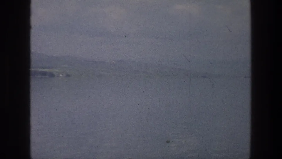 Sea of Galilee landscape in soft 8mm color, showing still water, haze, distant shore, and muted blue-gray tones.