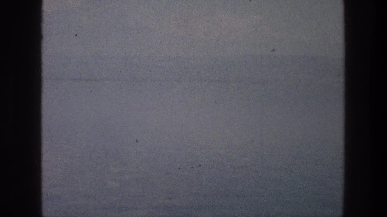 Soft, hazy water and sky seen through dark vertical window edges.