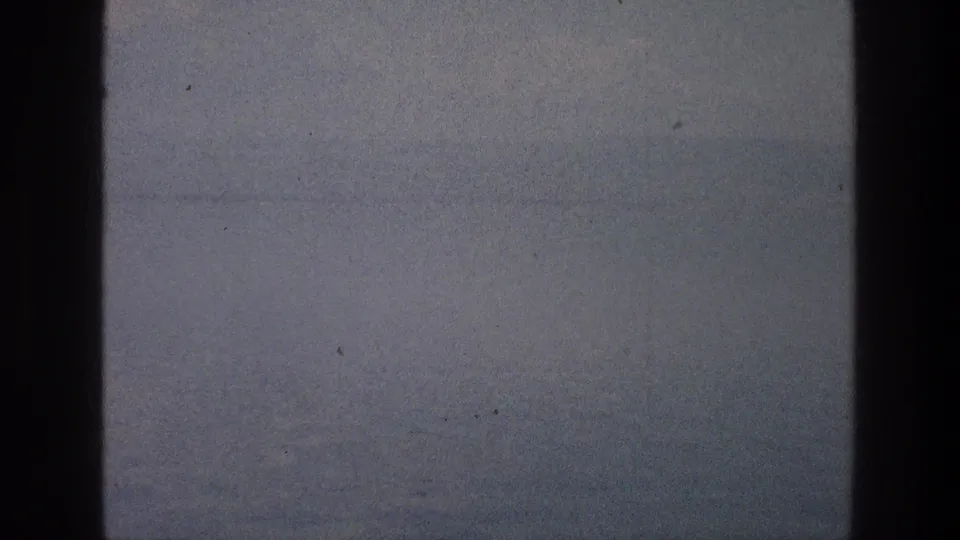 A dim 1976 8mm view toward the Sea of Galilee, with water and sky mostly obscured by dark window framing.