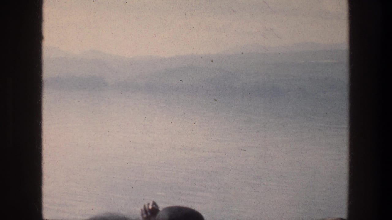 Sea of Galilee water and distant hills appear through a window frame, with part of a passenger head silhouetted at the lower edge.