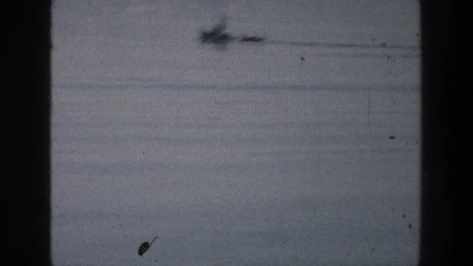 Soft 1976 8mm frame from the Sea of Galilee showing a blurred small craft-like object moving across pale water.