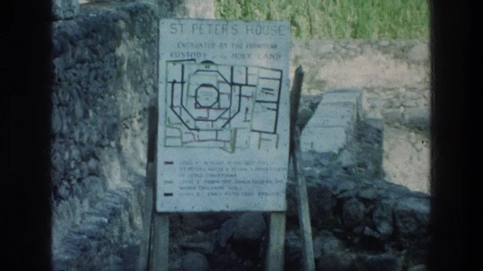 Informational board for St. Peter's House, showing an excavation plan beside stone ruins at the Sea of Galilee site.
