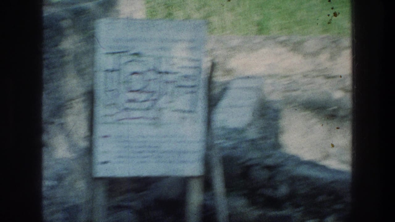 1976 8mm visitor view at the Sea of Galilee showing an informational site-plan sign beside weathered stone ruins.