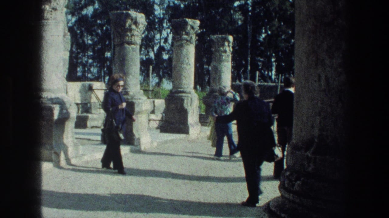 Tourists stand and walk among sunlit stone columns framed by dark foreground masonry.