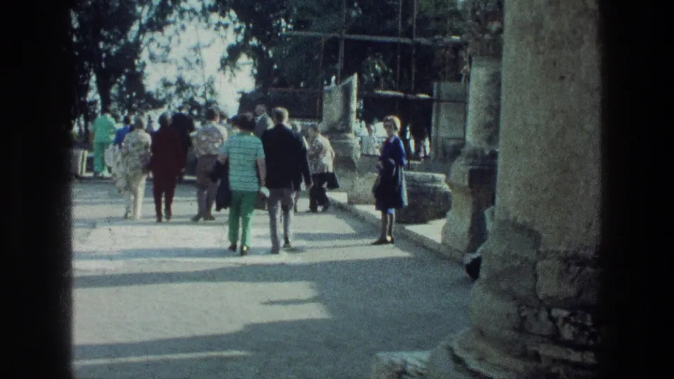 The handheld 8mm view follows tourists moving among ancient columns and stone walls at the Sea of Galilee location.