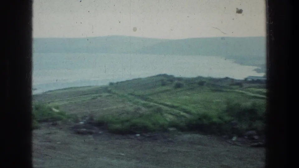 A 1976 travel shot looks over the Sea of Galilee, with green shoreline, water, and low hills in the distance.