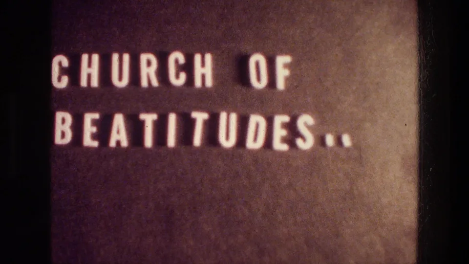1976 8mm view of the same Tabgha Church of Beatitudes sign, cropped close with white letters on a brown surface.