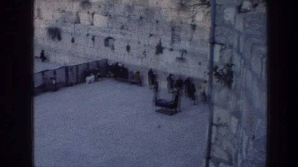 Soft, blue-tinted 1976 8mm view of people gathered near the Wailing Wall in Jerusalem.