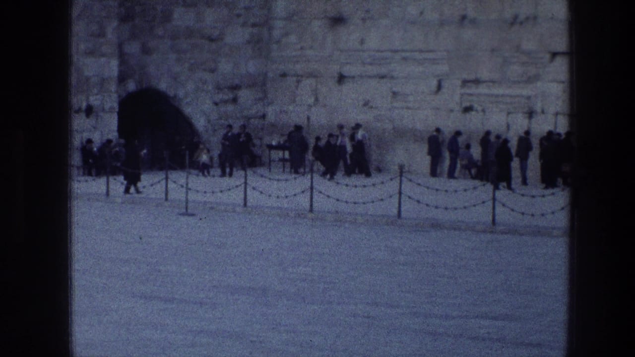 1976 8mm view of visitors gathered along the Western Wall in Jerusalem, with an arched opening and chains in the foreground.