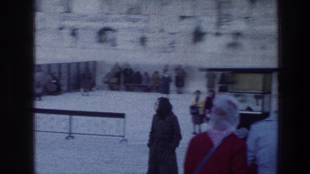 People standing and walking in a stone courtyard near the wall.