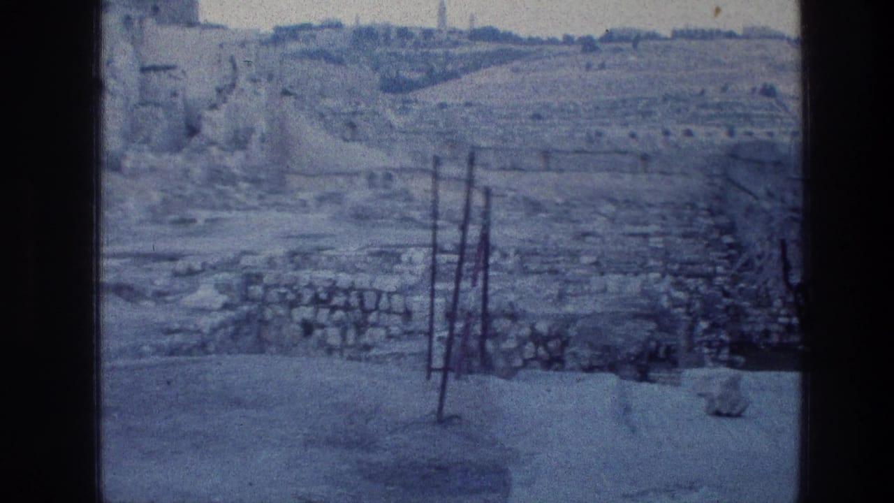 Rocky ruins and low stonework beyond a paved area.