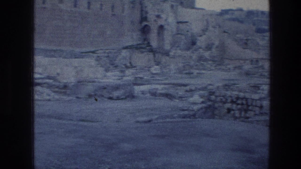 Weathered stone wall and rubble seen through a dark 8mm film frame border.
