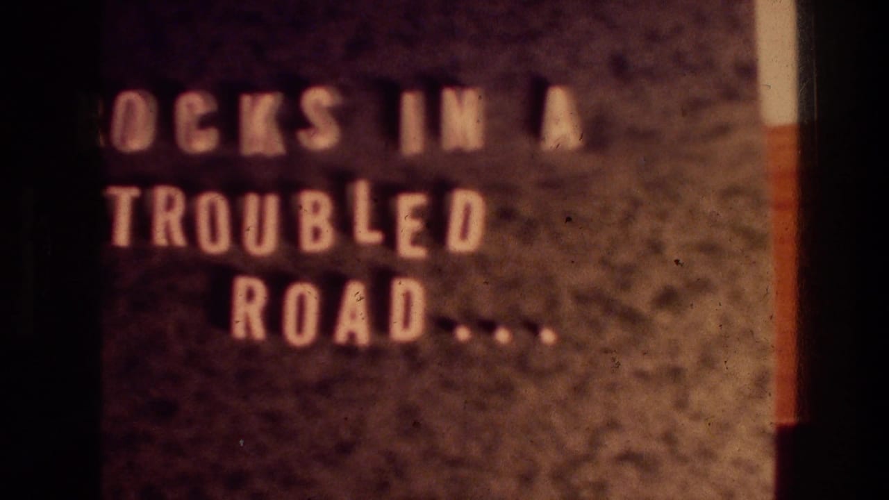 Soft 8mm title card with partial white lettering on a dark textured background.