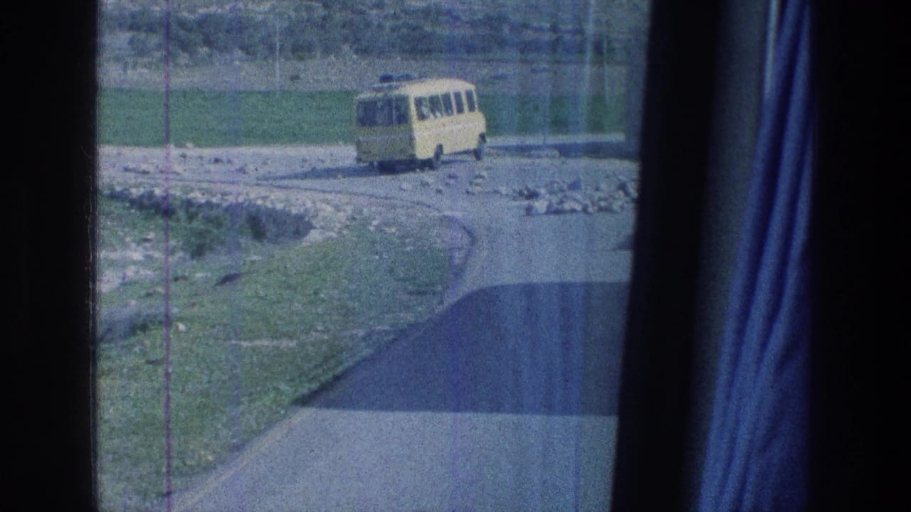 1976 Jerusalem-area road view with a yellow bus continuing along the bend, framed by vehicle interior edges.