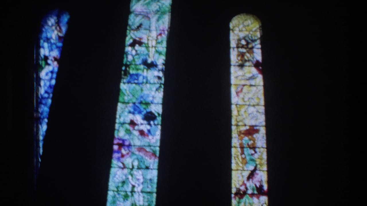 Colorful stained glass panels seen in a dark church-like interior in the Zurich home-movie footage.