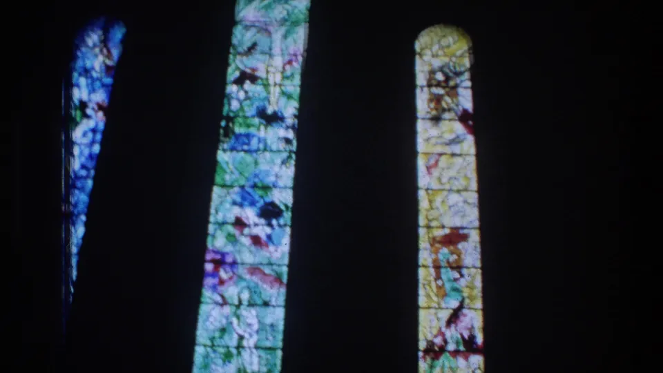 Colorful stained glass panels seen in a dark church-like interior in the Zurich home-movie footage.
