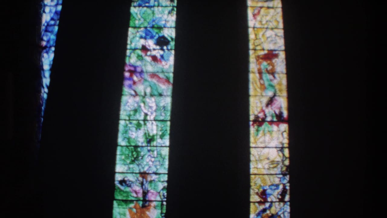 Zurich church windows on 8mm film, showing colorful religious glass panels in shadowed interior space.