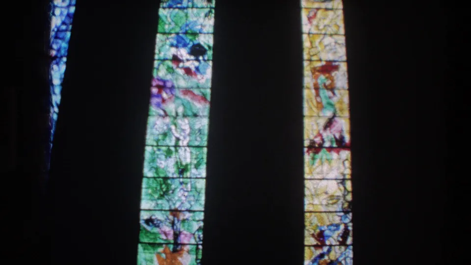 Zurich church windows on 8mm film, showing colorful religious glass panels in shadowed interior space.