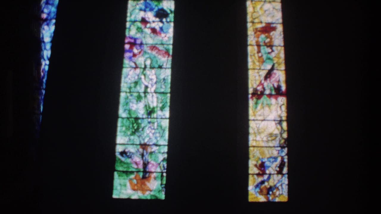 1976 Zurich church interior view with backlit stained glass and strong contrast from the surrounding darkness.