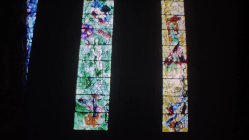 1976 Zurich church interior view with backlit stained glass and strong contrast from the surrounding darkness.