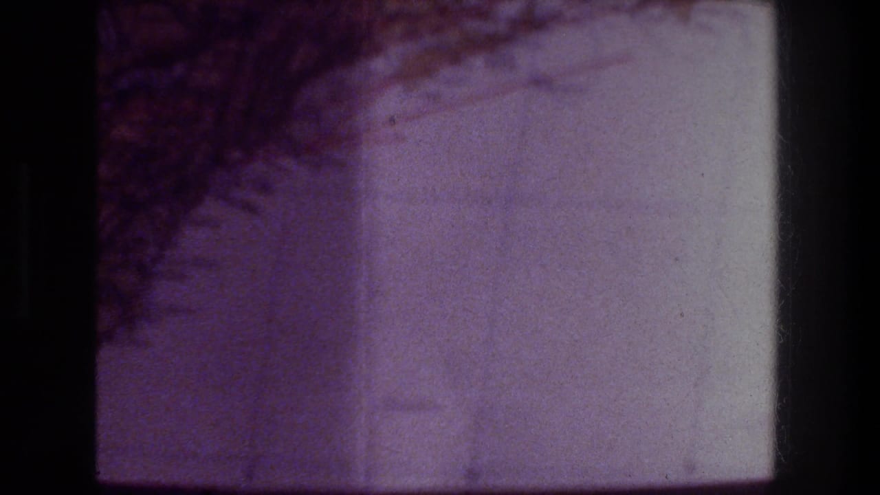 1976 Zurich 8mm frame showing faint square lines on paper, a dark diagonal texture, and visible black gate edging.