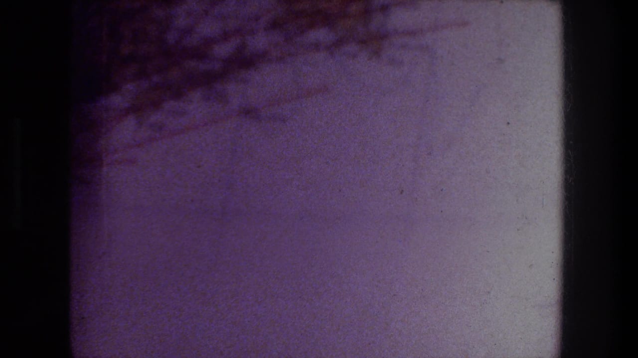 1976 Zurich home-movie frame showing a close view of a printed map page with pale areas, brown shading, and soft 8mm color shift.