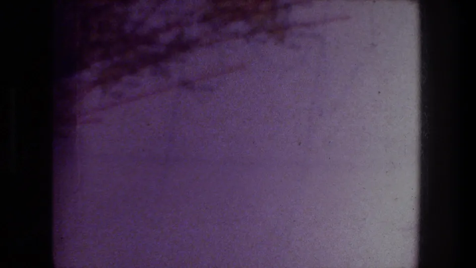 1976 Zurich home-movie frame showing a close view of a printed map page with pale areas, brown shading, and soft 8mm color shift.