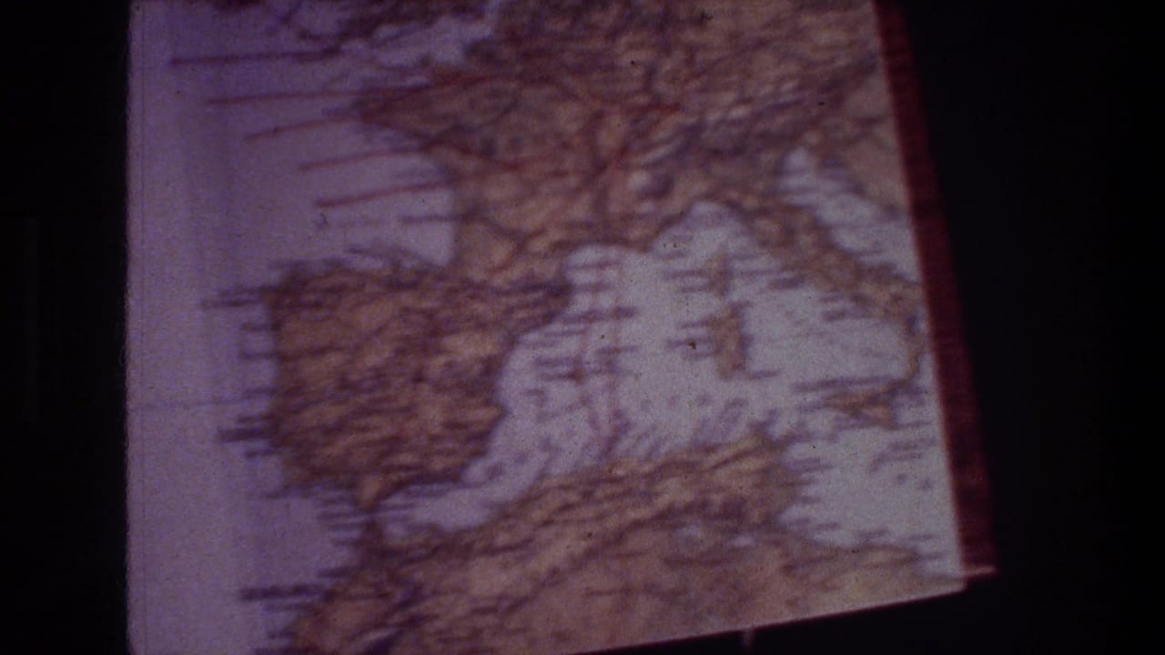 A second 8mm frame of the worn travel map, softly focused and tinted purple, with grid markings visible.