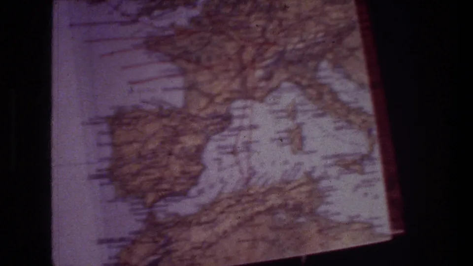 A second 8mm frame of the worn travel map, softly focused and tinted purple, with grid markings visible.