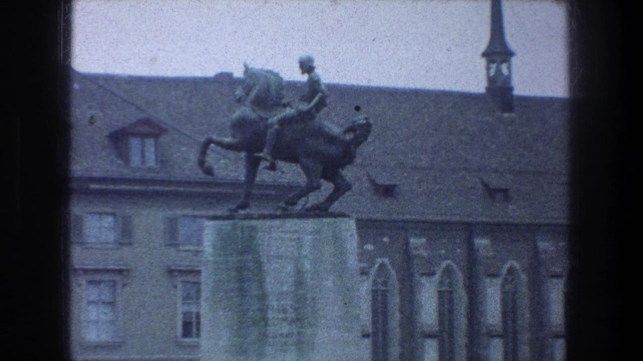 Zurich, 1976: a man on horseback statue stands above a stone base, framed against historic rooflines and a narrow spire.