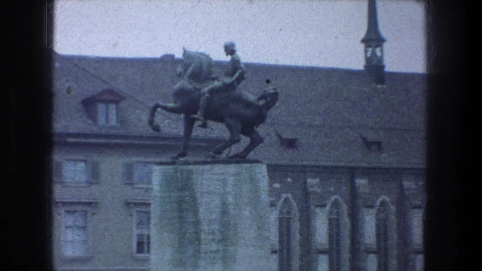Zurich, 1976: a man on horseback statue stands above a stone base, framed against historic rooflines and a narrow spire.