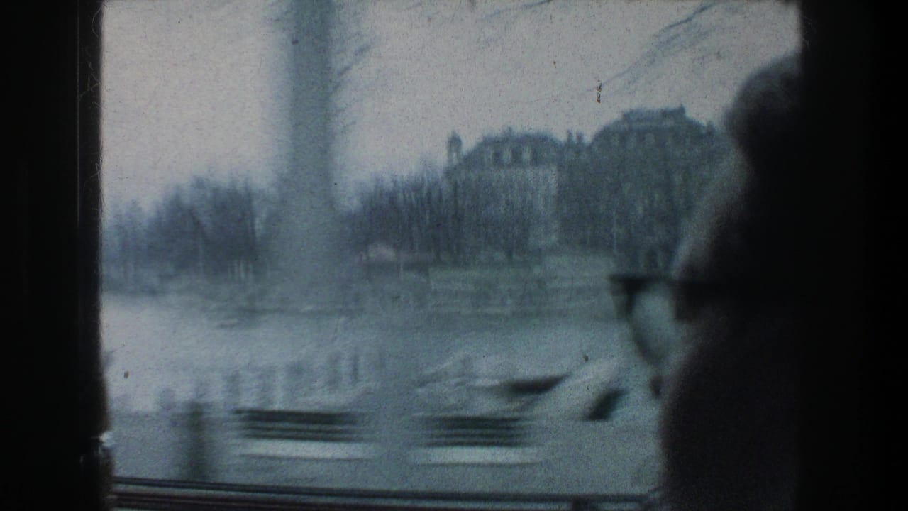 Zurich waterfront buildings and lake edge appear through a moving window in 1976, with a bespectacled passenger partly visible.