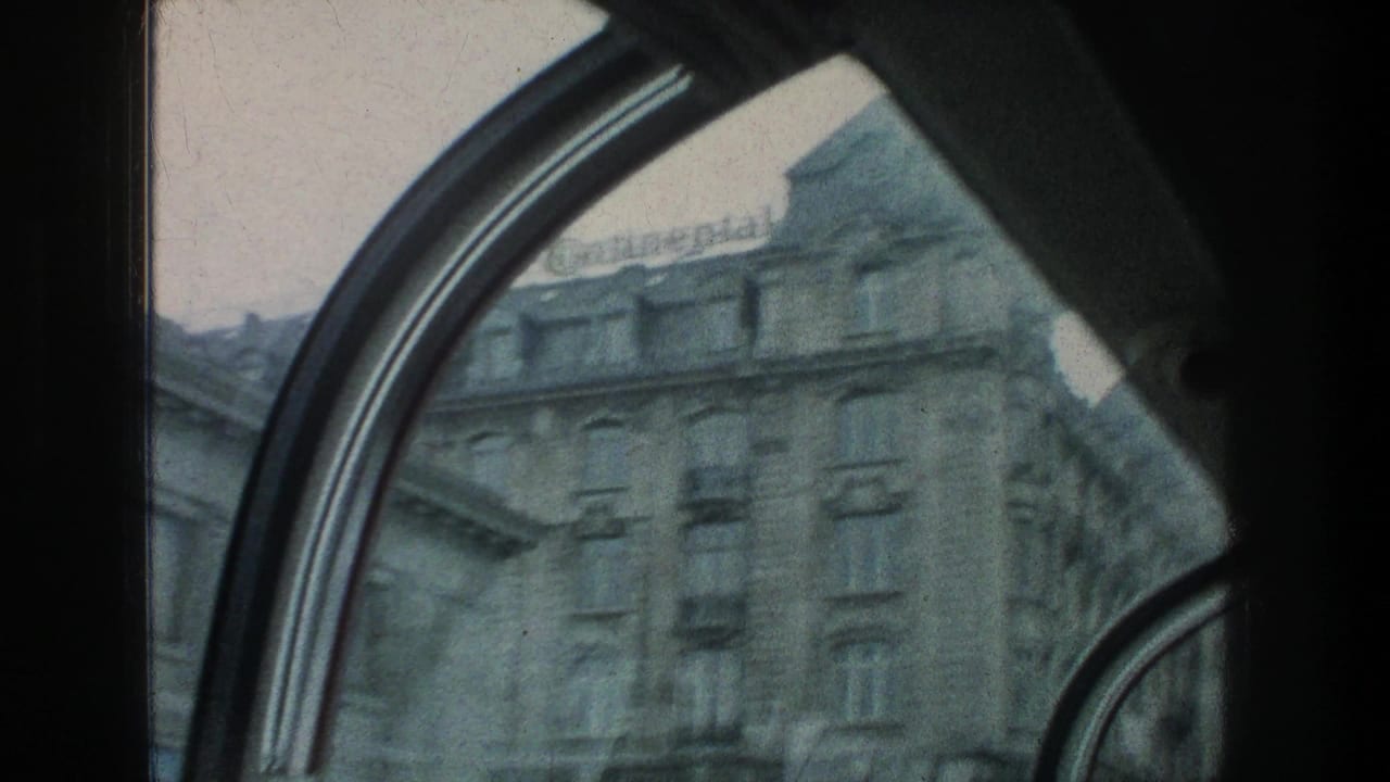 Upper stories of a stone building viewed through curved window framing.