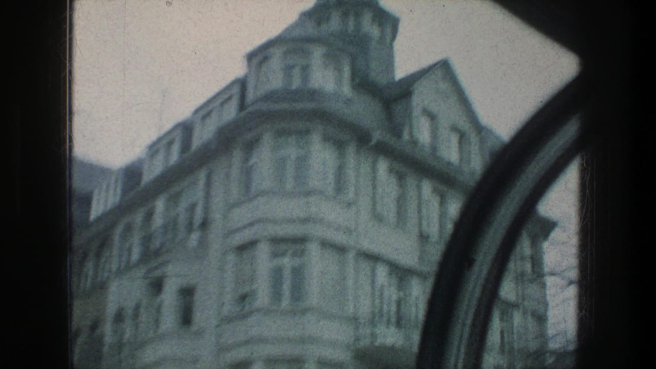 A rounded corner facade in Zurich appears in soft 1976 8mm color, framed by a dark curved window edge during travel.