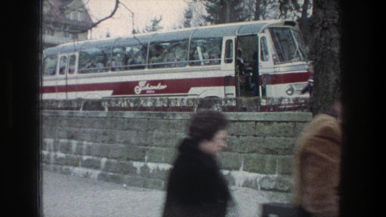 1976 Zurich street view with a red-and-white bus stopped behind a stone wall and pedestrians partly obscuring the camera.
