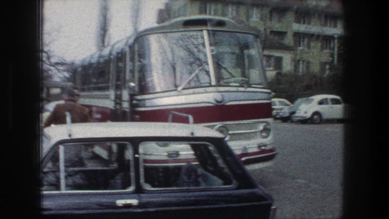 1976 Zurich street frame with the front of a red-and-white bus, parked compact cars, pedestrians, and residential buildings.