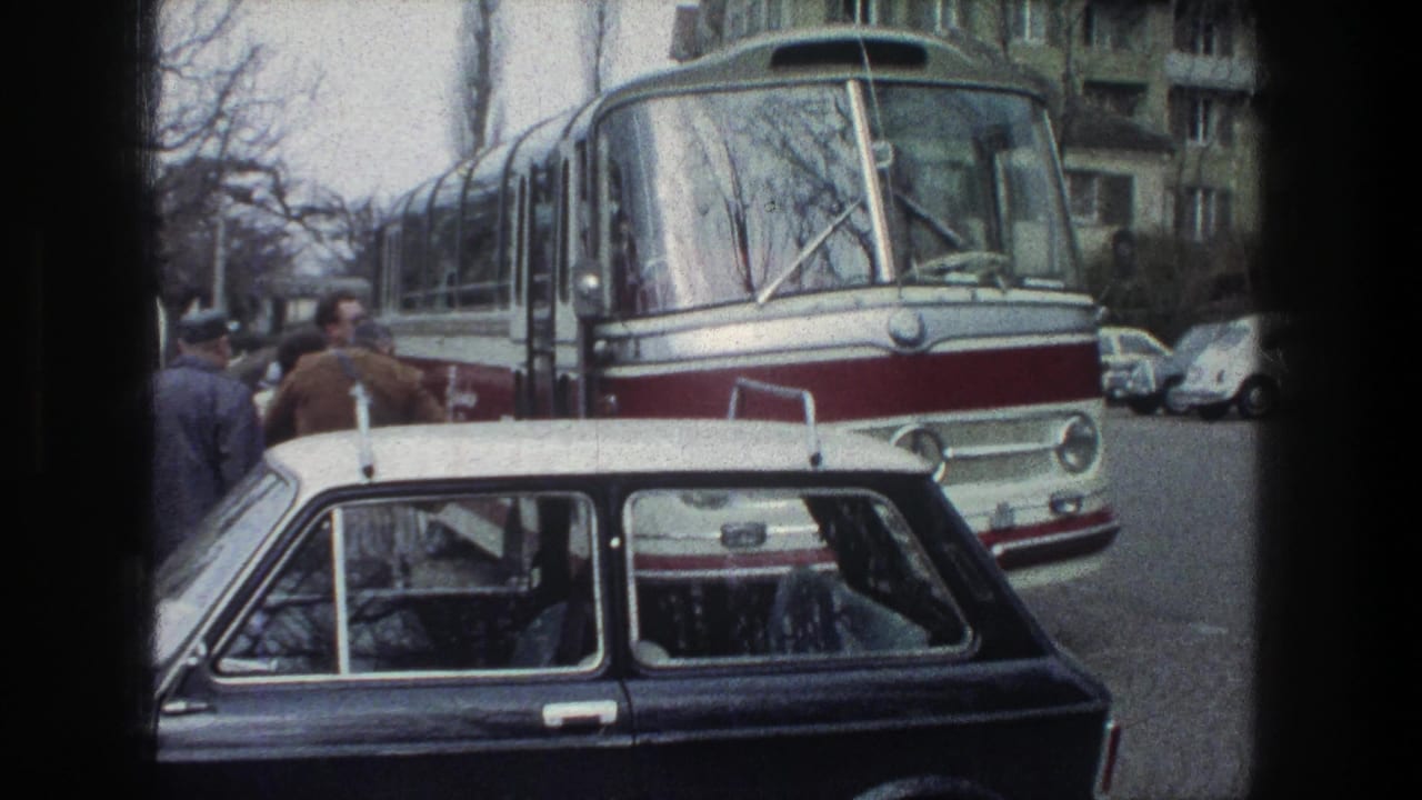 1976 Zurich street view of a red-and-white bus facing the camera as pedestrians stand near the curb and a dark car is parked in front.