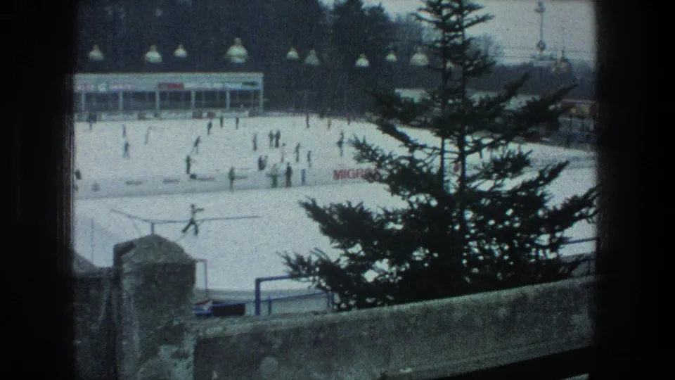 1976 Zurich winter rink scene framed by a pine tree and stone wall, with small skater figures, overhead lamps, signage, and a low rink building.