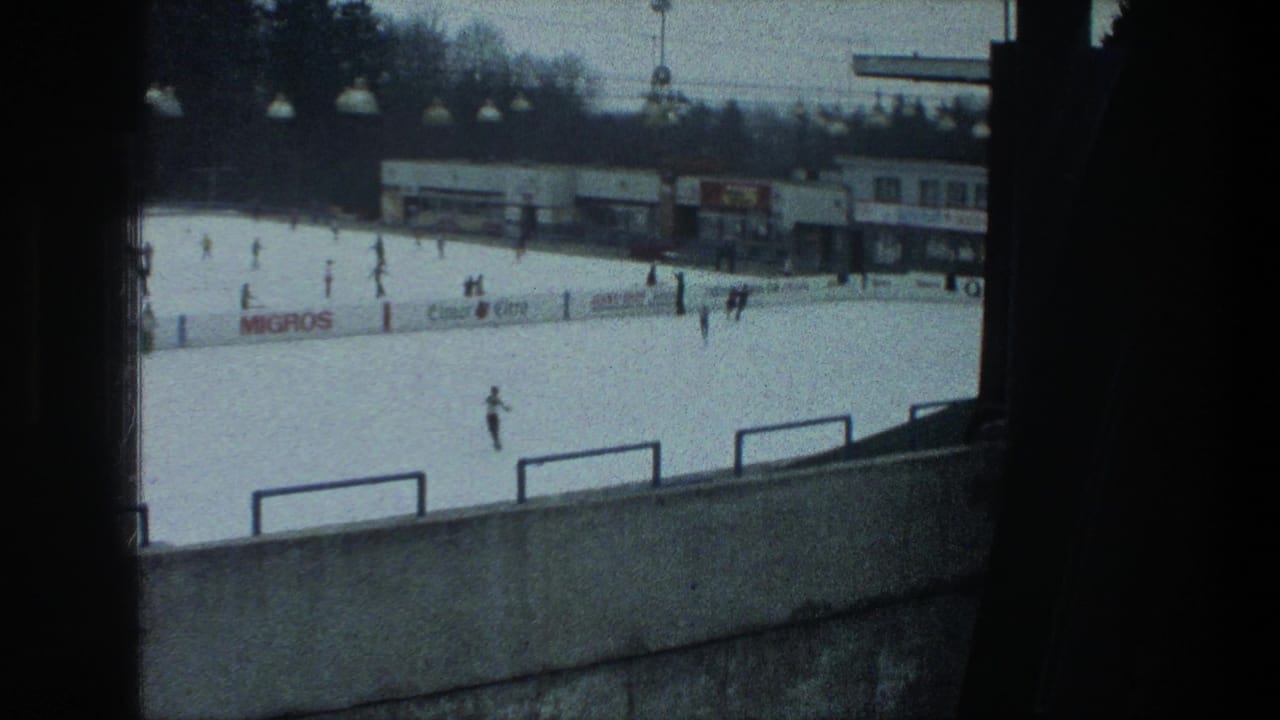 Zurich outdoor rink in 1976 with skaters spread across the ice, foreground railings, lamp fixtures, buildings, and visible signage.