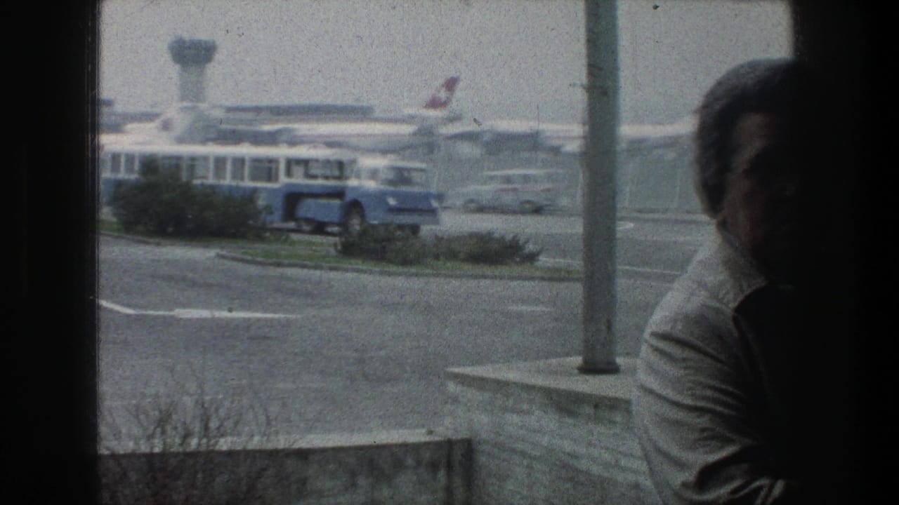 1976 Zurich airport view through terminal glass showing a blue shuttle bus, parked Swissair-marked jets, and a partially visible observer.