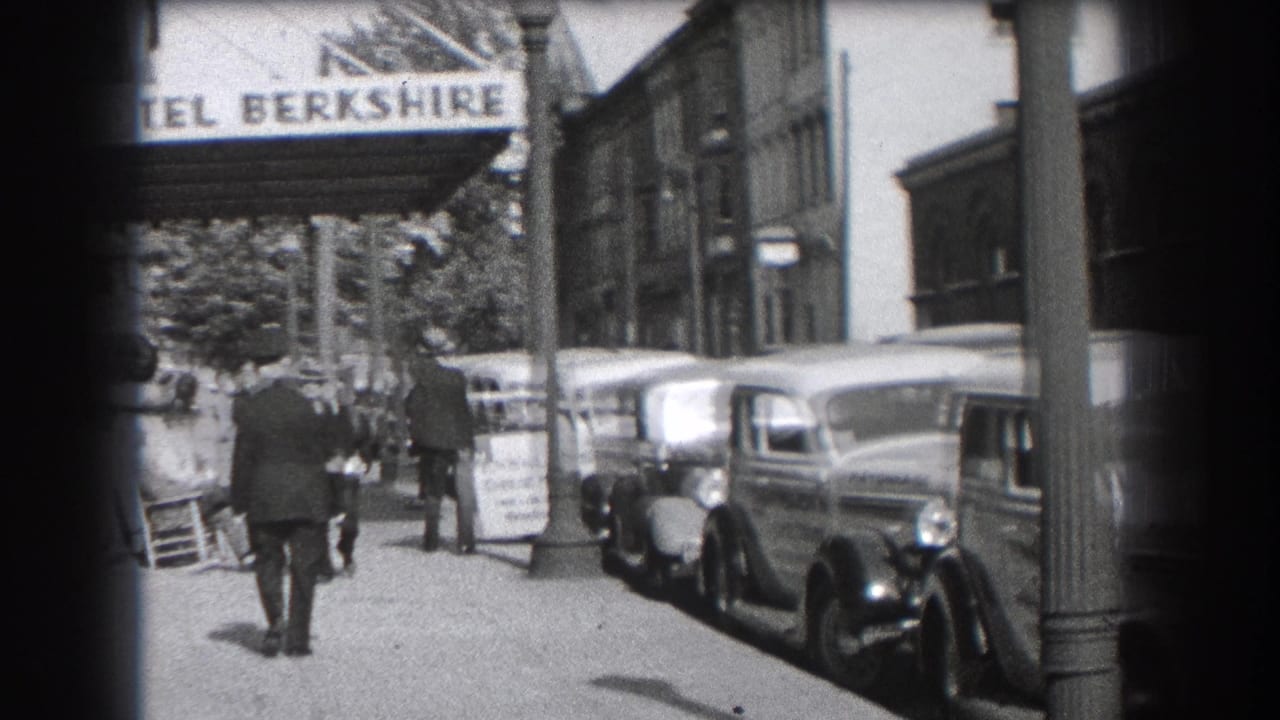 Sidewalk outside Hotel Berkshire with pedestrians, parked cars, and the hotel sign overhead.