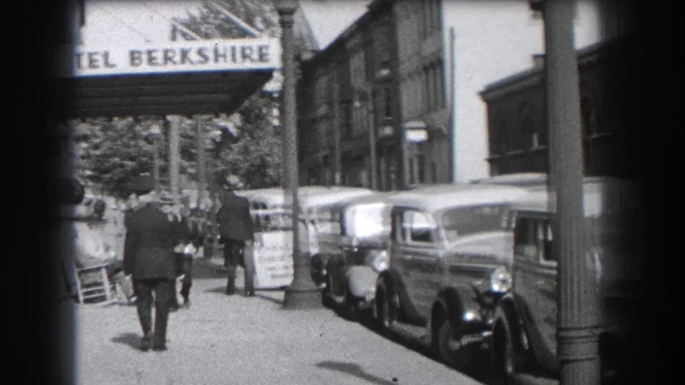 1938 Reading, Pennsylvania sidewalk view outside Hotel Berkshire, with pedestrians walking past parked cars beneath the visible hotel sign.