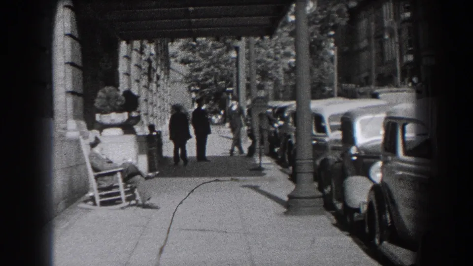 1938 Reading sidewalk scene near the Hotel Berkshire entrance, showing pedestrians beneath an awning beside a line of parked cars.