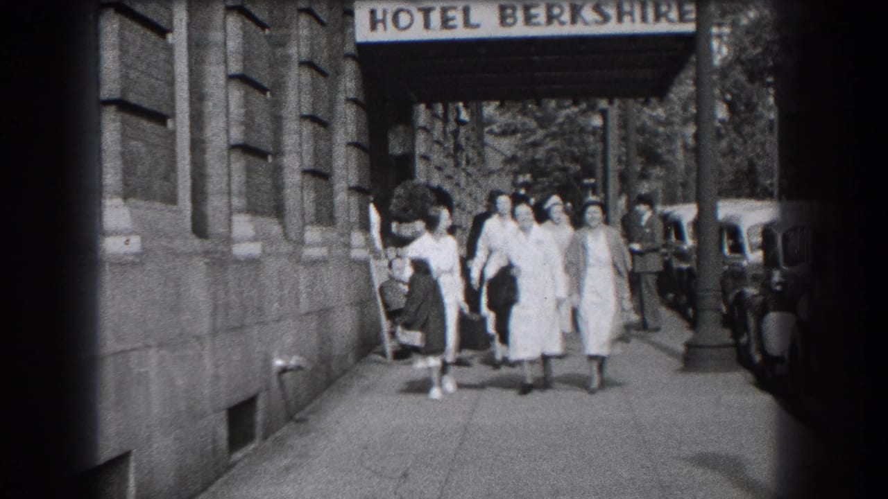 The group advances down the sidewalk outside the Hotel Berkshire in Reading, Pennsylvania, framed by the awning and curbside cars.