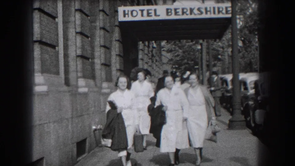 Closer 1938 home-movie view of women in nurse-style uniforms walking together beside a stone building in Reading, Pennsylvania.