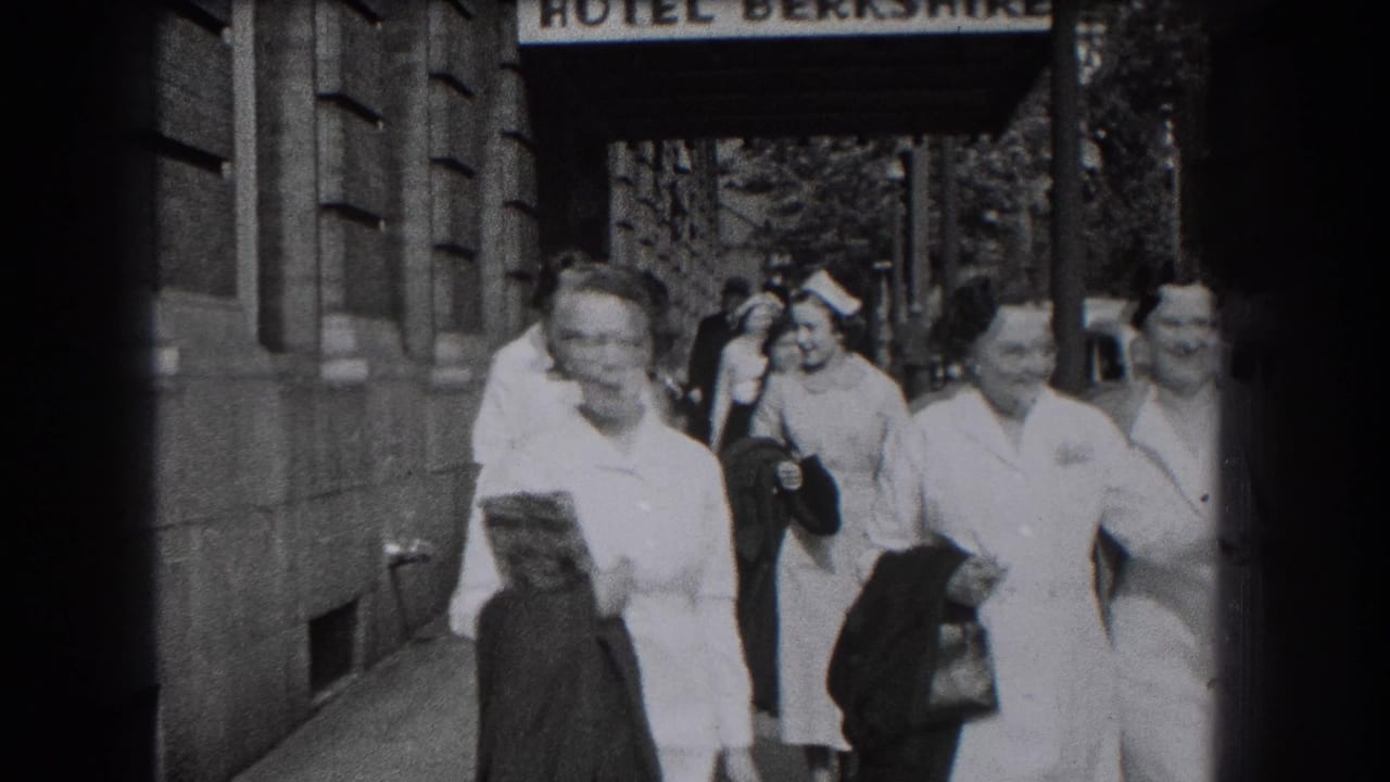 Uniformed nurses and other pedestrians move along the sidewalk under the Hotel Berkshire sign in Reading, Pennsylvania.