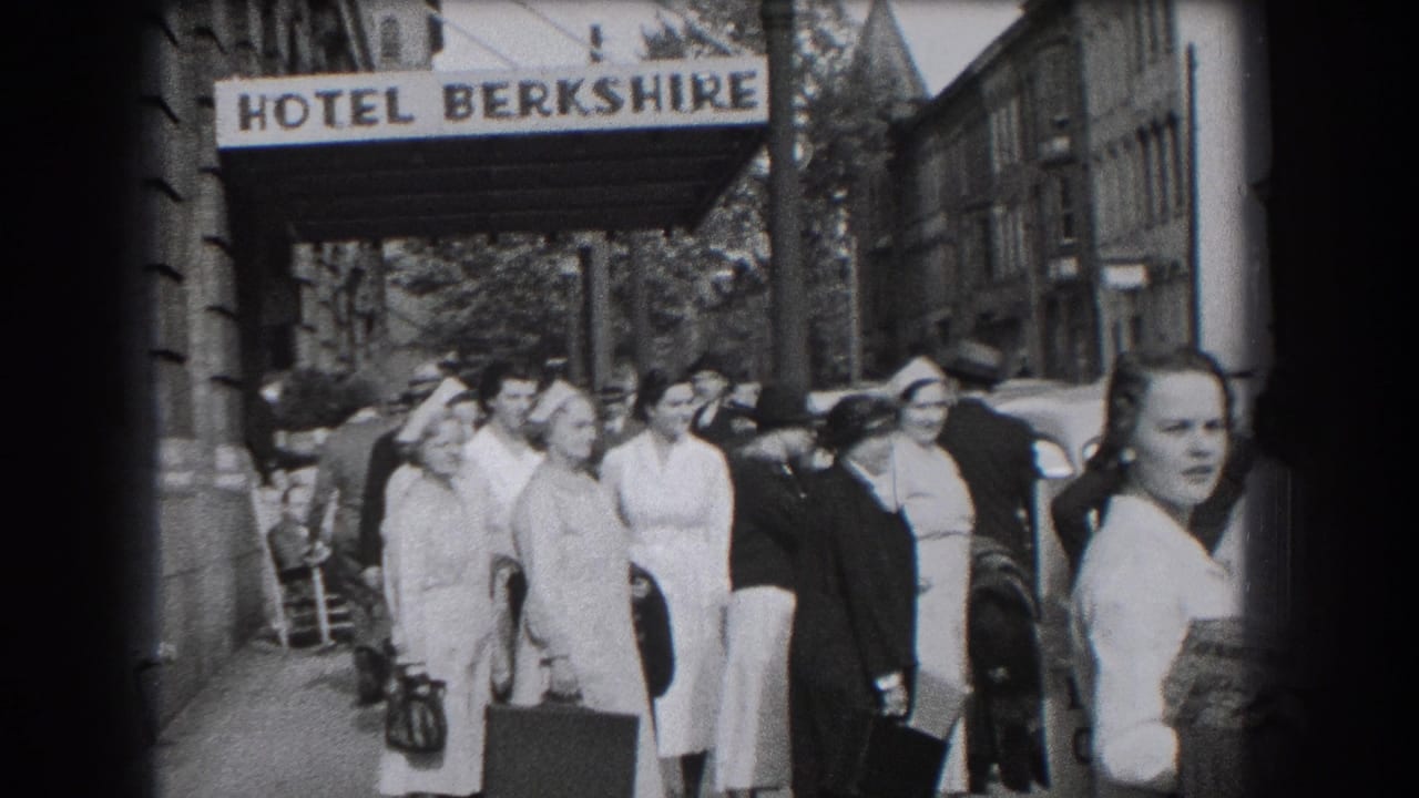 1938 hotel-side sidewalk view in Reading showing uniformed women with bags, a nearby car, and pedestrians at the curb.
