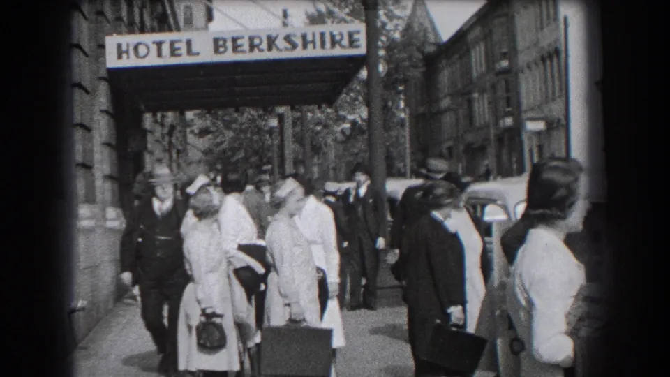 Reading, Pennsylvania hotel exterior with a sidewalk crowd, luggage, uniformed women, suited men, and the Hotel Berkshire sign overhead.