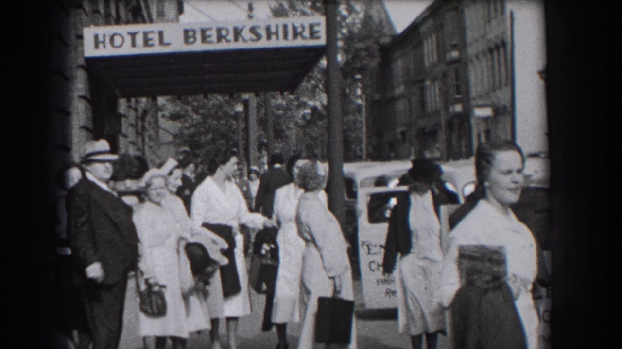 Crowded sidewalk outside the Hotel Berkshire in Reading, Pennsylvania, with passersby, luggage, cars, and storefront edges visible.